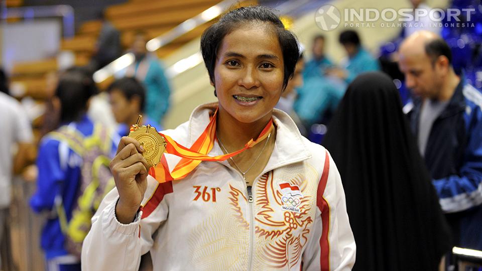 Moria Manalu memperlihatkan keping emas usai menjuarai nomor 65kg putri. 